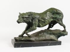A BRONZE OF A PROWLING WOLF ON A ROCK, mounted on a marble base. 17ins long.