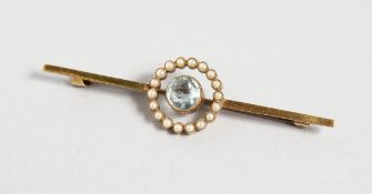 A 15CT GOLD BAR BROOCH, set with a single aquamarine surrounded by a band of pearls. 2.25ins long.