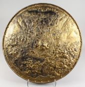 A LARGE EUROPEAN GILDED METAL CIRCULAR CHARGER depicting a battle scene. 25ins diameter.
