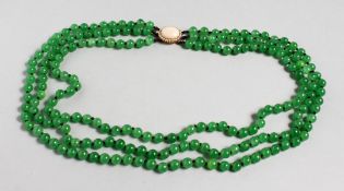 A THREE ROW STRING OF JADE BEADS, with an 18ct gold and cabochon coral clasp. 20ins long.