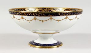 A PORCELAIN PEDESTAL BOWL, in the style of Noritake, painted with swans on a lake. 10ins diameter.