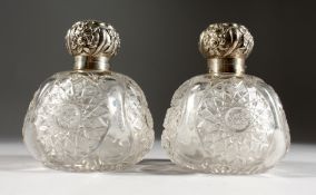 A PAIR OF CUT GLASS CIRCULAR PERFUME BOTTLES with silver tops.