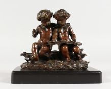 A SUPERB SMALL 19TH CENTURY BRONZE OF TWO PUTTI reading a book on a metal base. 4.5ins wide.