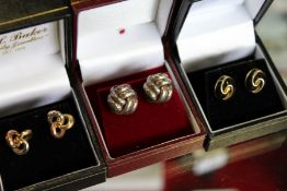 A pair of tri-colour knot earrings and two pairs of similar earrings.