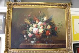 A large and impressive still life of flowers in an urn on a ledge, in a decorative gilt frame.