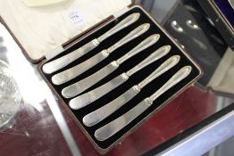 A cased set of six silver handled butter knives.