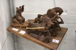 A carved wood model of a horse drawn sleigh being ridden on by a bear.