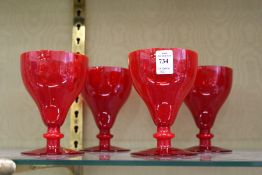 A set of four red glass goblets.