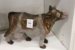 A carved and painted wooden model of a cow.