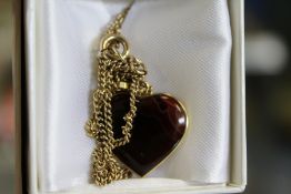 A gold and hardstone heart shaped pendant and chain.