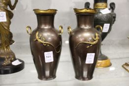 A pair of spelter twin handled vases decorated with lizards.