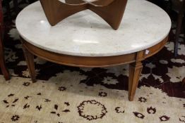 A circular marble top coffee table on tapering square legs.