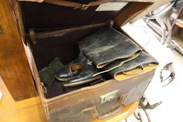 An old leather trunk containing a pair of leather riding boots.