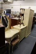 A four piece cream painted bedroom suite comprising wardrobe, chest of drawers, dressing table and