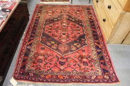 A Persian style rug, red ground with stylized decoration.