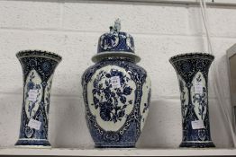 A Dutch Delft style blue and white three piece garniture comprising of a lidded jar and a pair of
