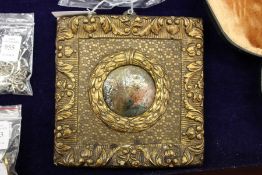 A small circular painting of figures in a decorative frame.