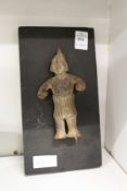 A small eastern pottery figure mounted on a board.