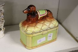 A pottery box and cover modelled as a dog seated on a cushion.