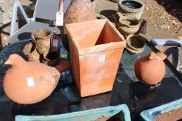 A pair of terracotta bird shaped garden ornaments and a square shaped pot.