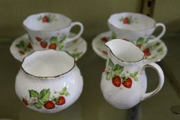 A pair of cups and saucers with cream jug and sugar bowl, decorated with strawberries.