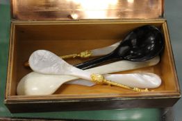 A copper cigarette box and decorative spoons.
