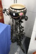 A Victorian floral decorated jardiniere on later wrought iron stand.
