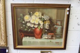 A still life of flowers in a red vase with other items on a table, oil on canvas.