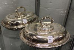 A pair of plated oval entree dishes and covers.