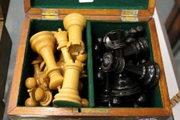 A box containing a quantity of ebony and box wood chess pieces.