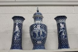 Chinese style blue and white decorated garniture comprising a lidded vase and a pair of sleeve