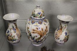 A continental pottery garniture modelled as a lidded jar and a pair of baluster shaped vases, all
