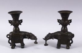 A PAIR OF CHINESE BRONZE ELEPHANT FORMED CANDLE STICKS, each with an object in thier mouth and a