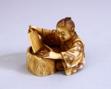 A JAPANESE MEIJI PERIOD CARVED IVORY OKIMONO - the figure seated above his hibachi waving his fan,