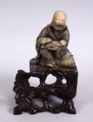 A GOOD CHINESE CARVED SOAPSTONE FIGURE OF LUOHAN & ABALONE SHELL INLAID HARDWOOD STAND, the figure
