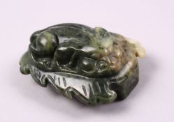 A CHINESE CARVED JADE BELT BUCKLE / DECORATION OF A RECUMBENT KYLIN, upon a leaf, 6.5cm.