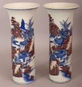 A PAIR OF CHINESE COPPER-RED & UNDERGLAZE-BLUE CYLINDRICAL PORCELAIN VASES, each decorated with a