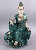 A LARGE CHINESE TURQUOISE GLAZED PORCELAIN FIGURE OF GUANYIN, in a seated position upon lotus,