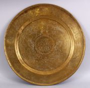 A GOOD CHINESE CARVED BRASS SYMBOLIC DISH, decorated with dragons and symbols / calligraphy, 46cm.
