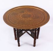 A FINE 19TH CENTURY ISLAMIC DAMASCUS BRASS TRAY ON WOODEN STAND, the tray with calligraphy, 67cm