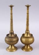 A PAIR OF INDIAN / ISLAMIC BRASS MOULDED ROSE WATER SPRINKLERS, with a ribbed central body, 23cm.