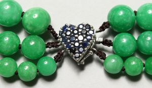 A JADE BEAD NECK with 14ct white gold and sapphire clasp.