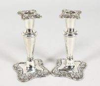 A SMALL PAIR OF SILVER CANDLESTICKS with shaped scrolled bases. 5.5ins high. Birmingham 1902.