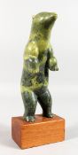AN INUIT COLOURED STONE CARVING OF A BEAR, standing on its back legs, on a wooden base. 9ins high.