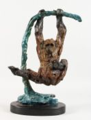AN UNUSUAL PAINTED BRONZE FIGURE OF AN ORANGUTAN SWINGING ON A BRANCH, on a marble base. 18ins