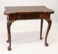 A GEORGE III MAHOGANY CARD TABLE, the fold-over top of shaped outline with four counter wells, green
