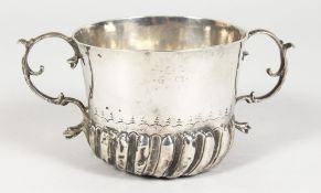 AN EARLY 18TH CENTURY TWO-HANDLED PORRINGER, semi fluted with scrolling handles, 3.5ins diameter.