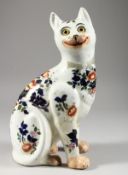 A GALLE PORCELAIN CAT, painted with flowers and glass eyes, (one leg repaired). 13ins high.