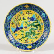 A CHINESE PORCELAIN PLATE, blue and yellow ground decorated with dragons. 8.75ins diameter.