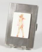 AN ENGINE TURNED SILVER CIGARETTE CASE, with a glamour model with long legs. Birmingham 1947.